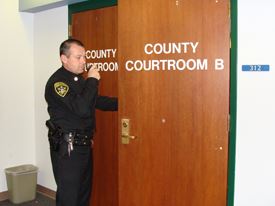 Court Security Officer Scott Rodbourn on radio standing outside of County Courtroom B